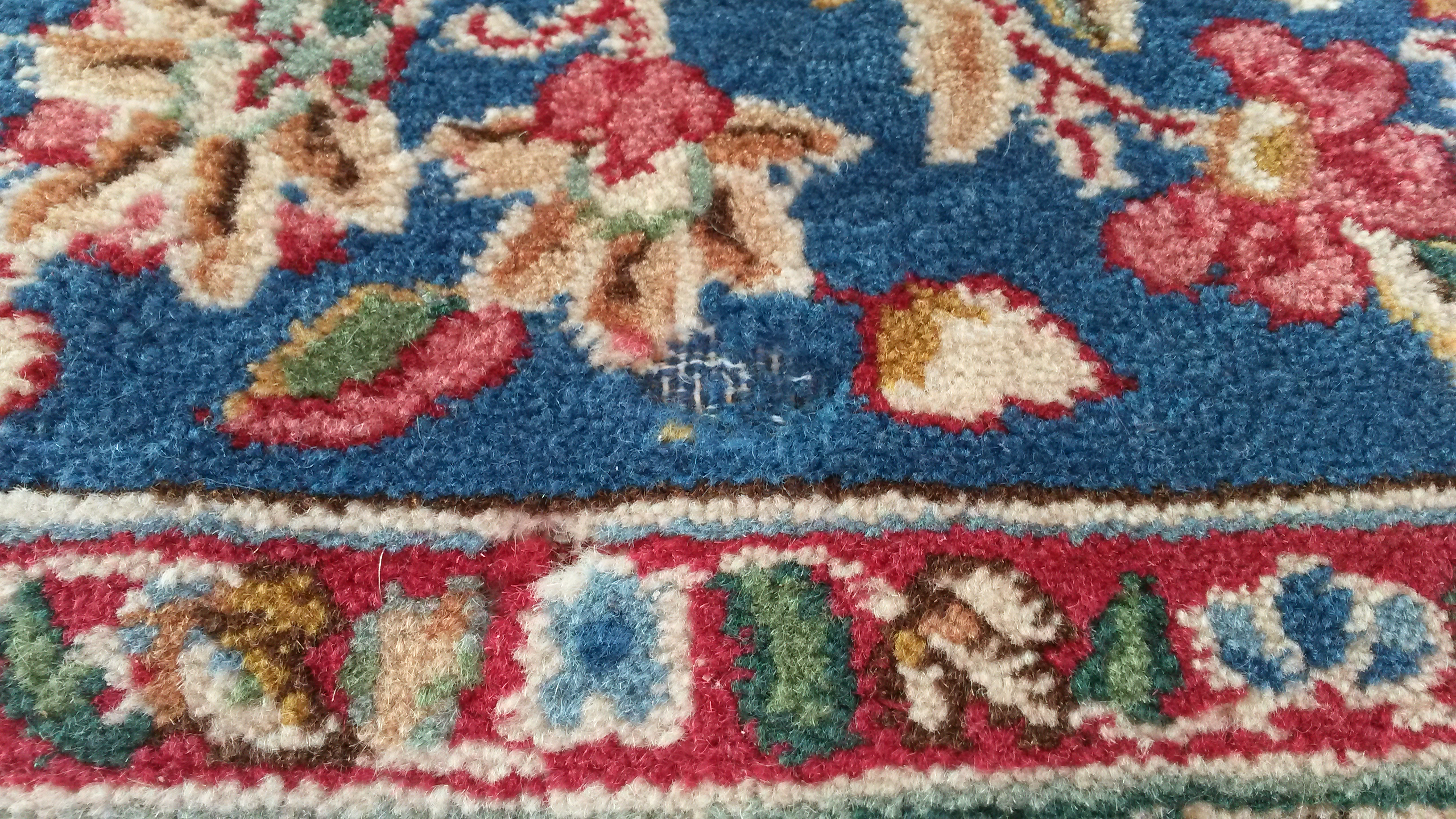 A Persian wool rug with damage caused by carpet moth