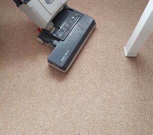An industrial upright vacuum cleaner cleaning a carpet prior to wet cleaning